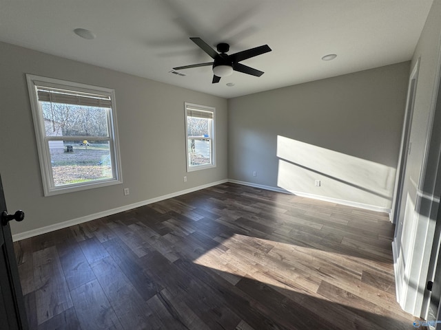 unfurnished room featuring a ceiling fan, dark wood-style flooring, baseboards, and visible vents