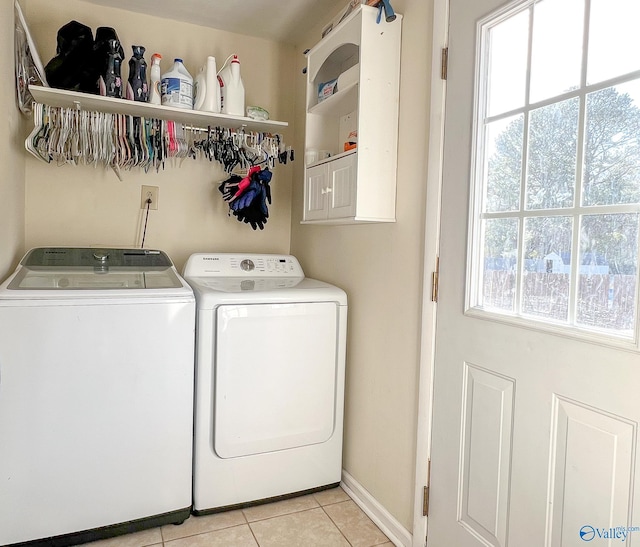 washroom featuring washing machine and dryer, laundry area, baseboards, and light tile patterned floors