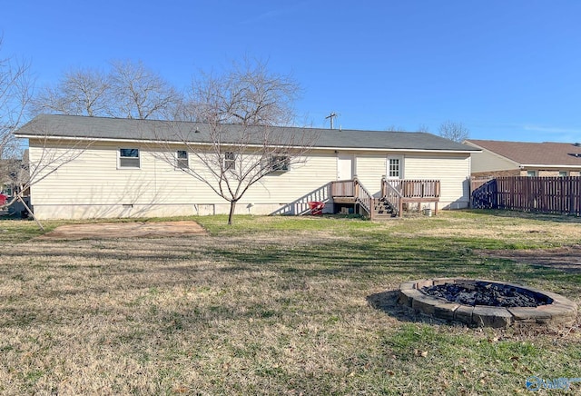 rear view of house featuring a fire pit, a lawn, and fence