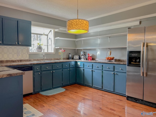 kitchen featuring crown molding, stainless steel appliances, a sink, and blue cabinets