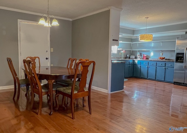 dining area featuring a notable chandelier, crown molding, light wood-style floors, a textured ceiling, and baseboards