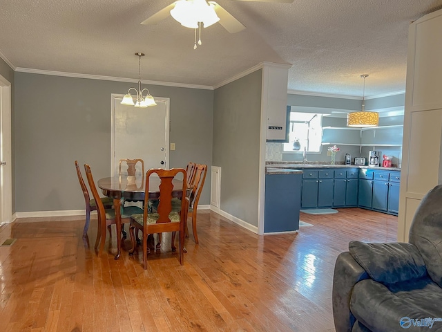 dining area with light wood-style floors, crown molding, a textured ceiling, and baseboards