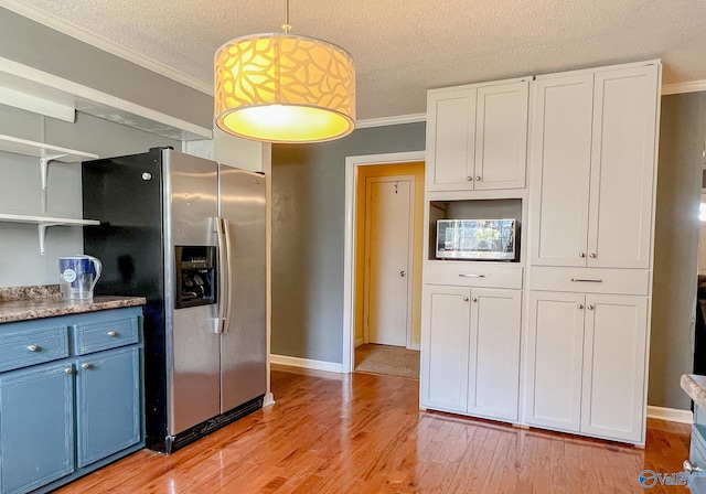 kitchen with white cabinets, pendant lighting, stainless steel refrigerator with ice dispenser, and light countertops