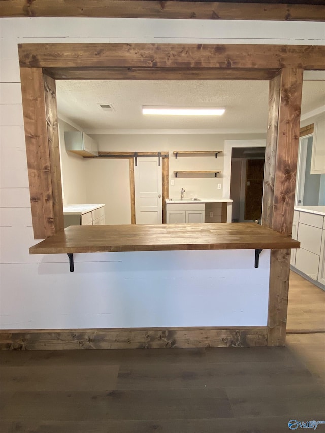 kitchen with sink, hardwood / wood-style flooring, a barn door, and a textured ceiling