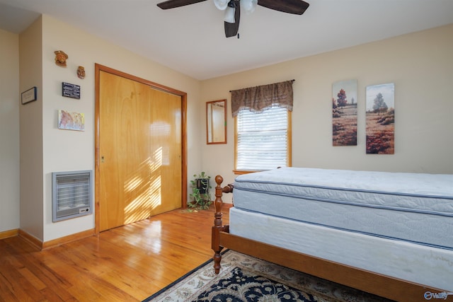 bedroom with a closet, hardwood / wood-style flooring, heating unit, and ceiling fan