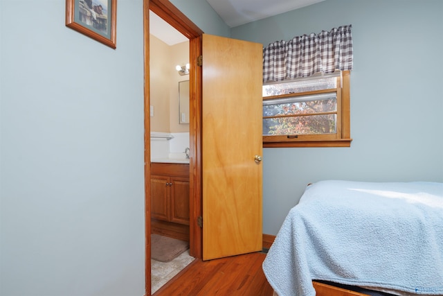 bedroom featuring connected bathroom, hardwood / wood-style flooring, and sink