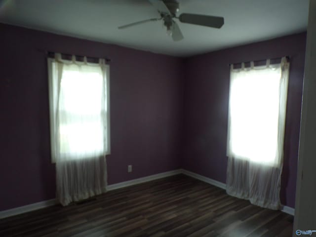 spare room featuring dark wood-type flooring, ceiling fan, and a healthy amount of sunlight