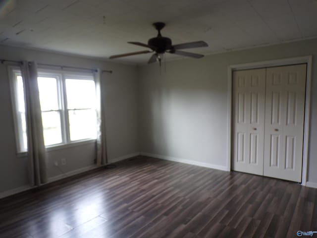 unfurnished bedroom featuring dark wood-type flooring, ceiling fan, and a closet