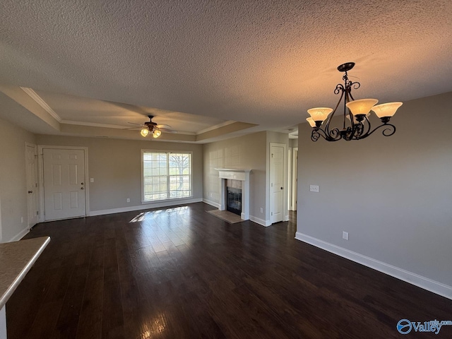 unfurnished living room featuring a raised ceiling, a textured ceiling, dark wood finished floors, a fireplace, and baseboards