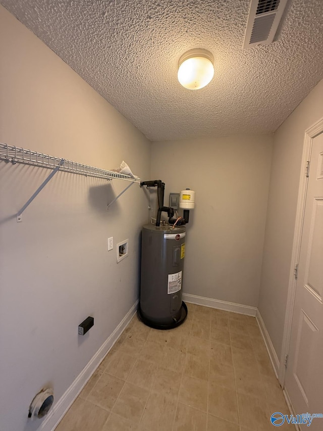 washroom featuring visible vents, baseboards, washer hookup, water heater, and laundry area