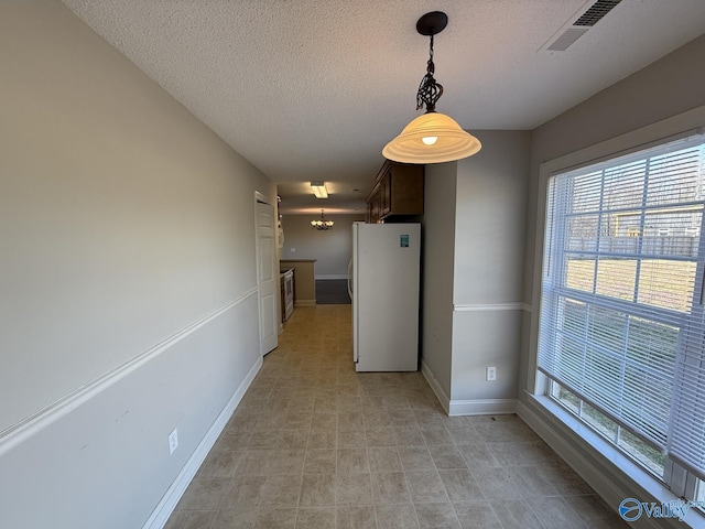 unfurnished dining area with visible vents, baseboards, and a textured ceiling