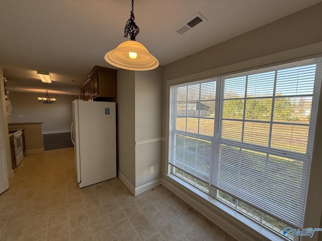 kitchen with white appliances, baseboards, visible vents, and a textured ceiling