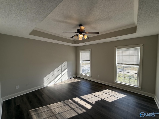 spare room featuring dark wood-style floors, baseboards, and a tray ceiling