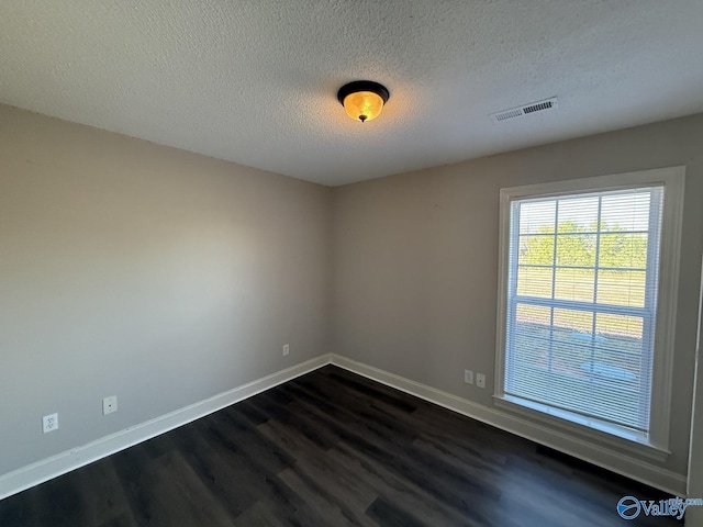 unfurnished room with dark wood finished floors, baseboards, visible vents, and a textured ceiling