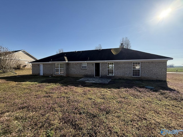 rear view of property with a yard, a patio, and brick siding