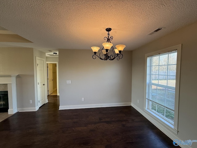 unfurnished dining area with a tiled fireplace, dark wood finished floors, baseboards, and a chandelier