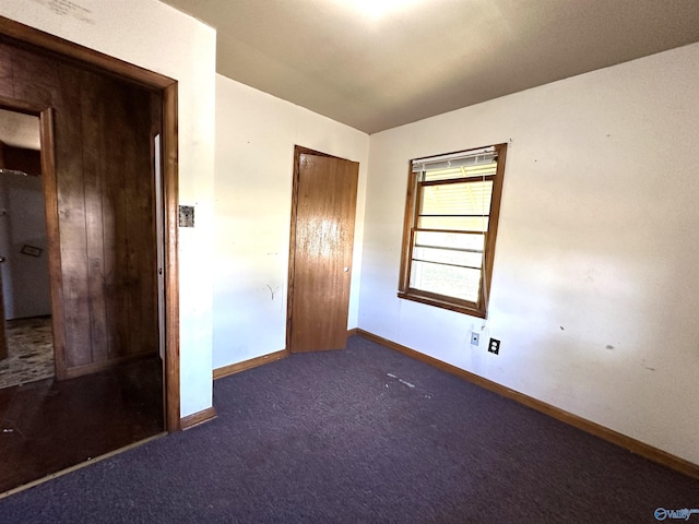 unfurnished bedroom featuring a closet and dark carpet