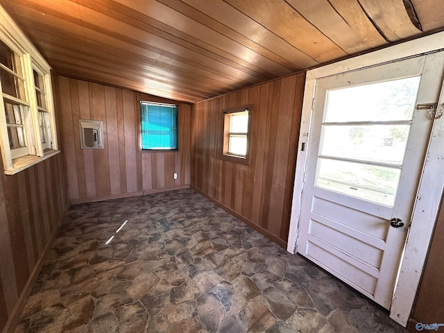 spare room featuring stone finish flooring, wood ceiling, and wooden walls