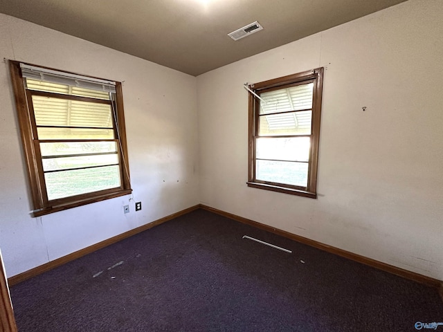 unfurnished room with visible vents, baseboards, and dark carpet
