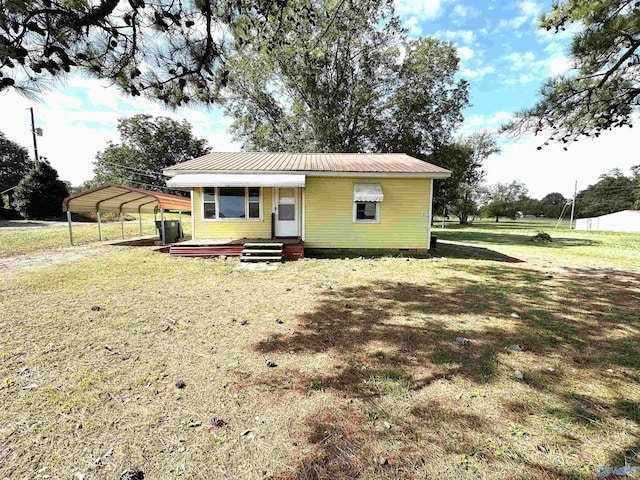 view of front facade featuring a front lawn, a detached carport, crawl space, and metal roof