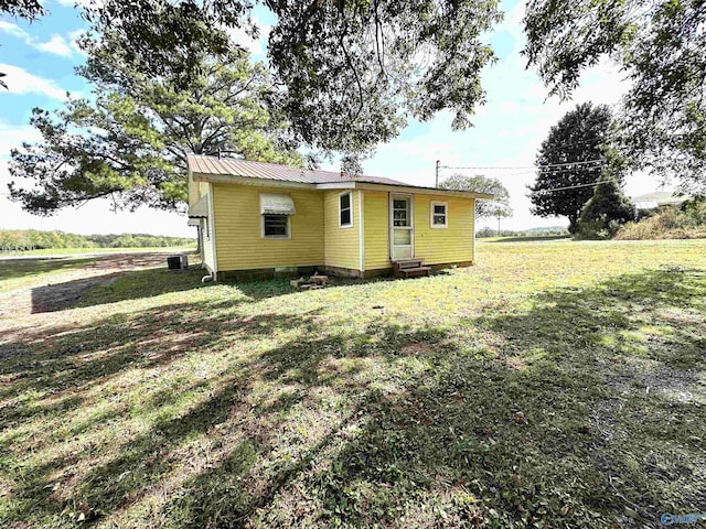 rear view of property featuring entry steps, central AC unit, and a yard