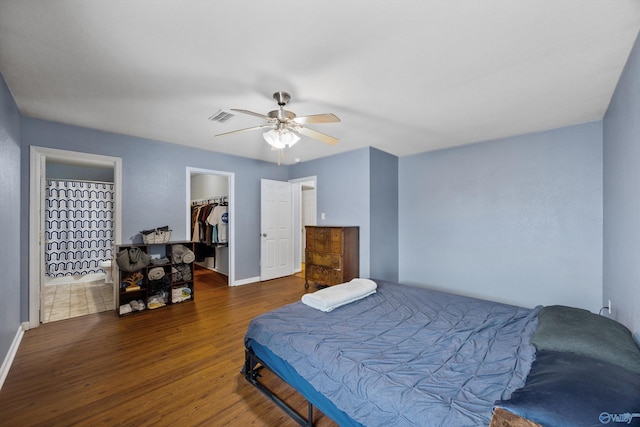 bedroom featuring ensuite bathroom, a walk in closet, dark hardwood / wood-style floors, a closet, and ceiling fan