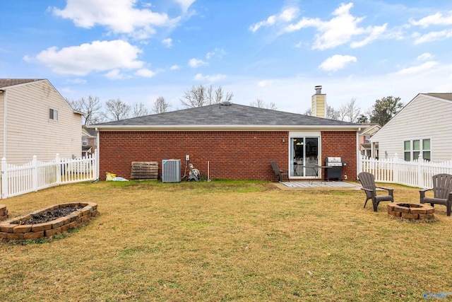 rear view of house featuring a lawn, cooling unit, and an outdoor fire pit