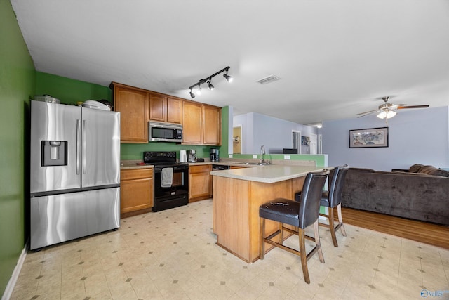 kitchen featuring sink, ceiling fan, stainless steel appliances, a kitchen breakfast bar, and kitchen peninsula