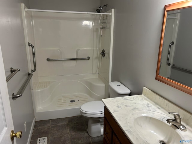 bathroom featuring tile patterned floors, vanity, toilet, and walk in shower