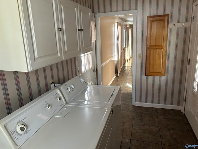 clothes washing area featuring cabinets, washing machine and dryer, and dark tile patterned flooring