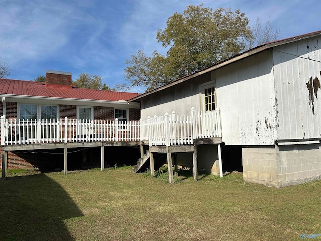 rear view of property featuring a deck and a yard