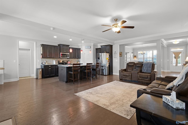 living area featuring baseboards, dark wood-style flooring, ceiling fan with notable chandelier, and ornamental molding