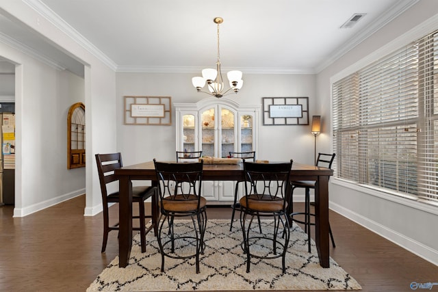 dining room with ornamental molding, visible vents, baseboards, and dark wood-type flooring