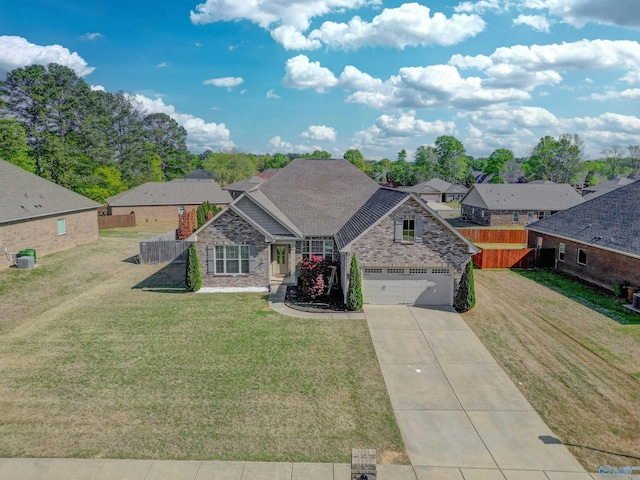 view of front facade featuring concrete driveway, a front yard, brick siding, and fence