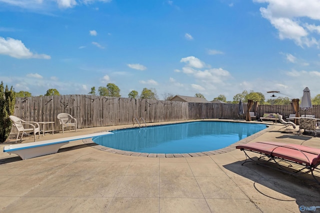 view of swimming pool featuring a fenced backyard, a fenced in pool, a patio, and a diving board