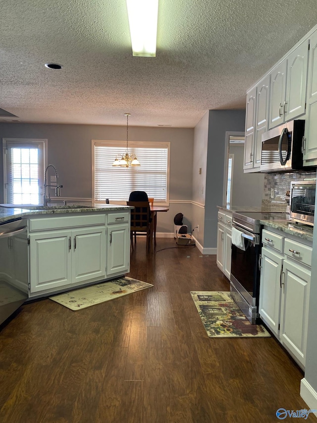 kitchen featuring appliances with stainless steel finishes, decorative light fixtures, dark hardwood / wood-style floors, decorative backsplash, and sink