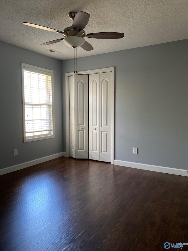 unfurnished bedroom featuring dark wood-type flooring, a closet, a textured ceiling, and ceiling fan