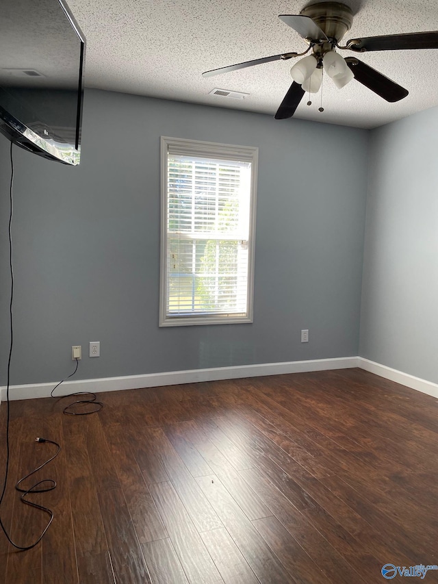 spare room with a textured ceiling, dark hardwood / wood-style floors, and ceiling fan