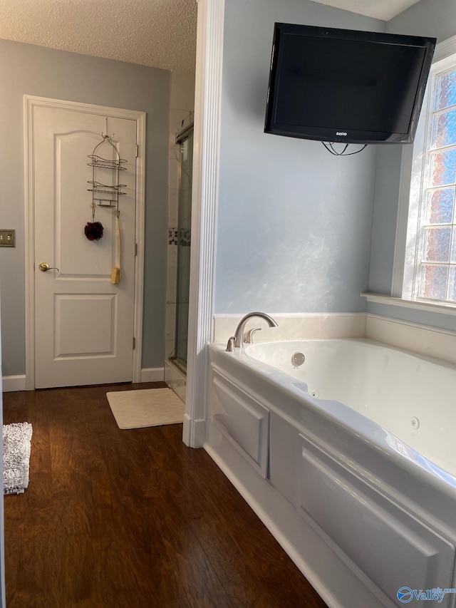 bathroom with independent shower and bath, wood-type flooring, and a textured ceiling