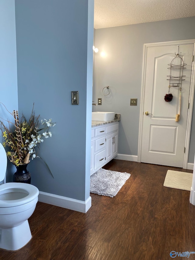 bathroom featuring toilet, vanity, a textured ceiling, and hardwood / wood-style flooring