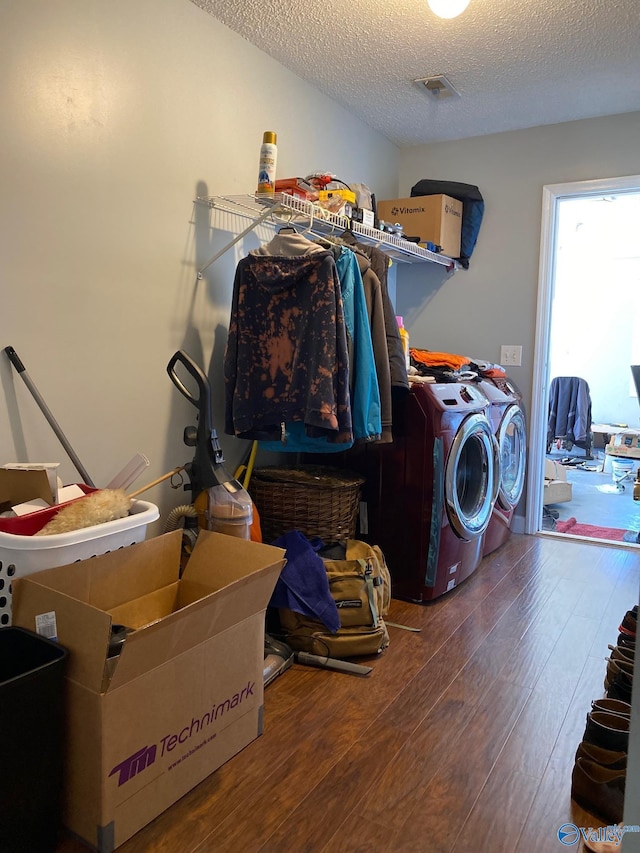 laundry room with wood-type flooring, separate washer and dryer, and a textured ceiling