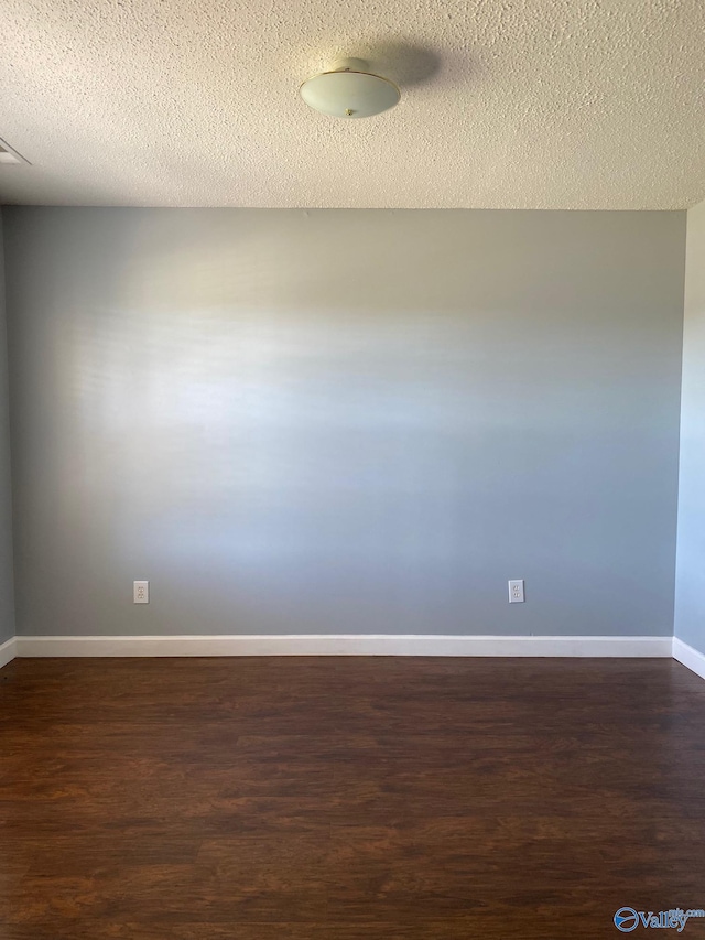 empty room featuring a textured ceiling and dark hardwood / wood-style floors