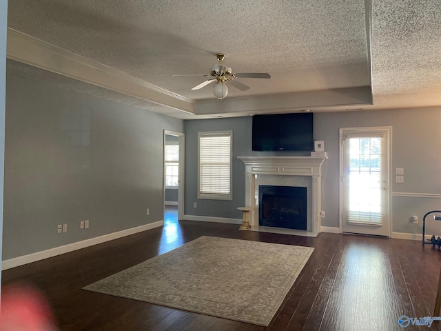 unfurnished living room with dark hardwood / wood-style flooring, a textured ceiling, ceiling fan, and a tray ceiling