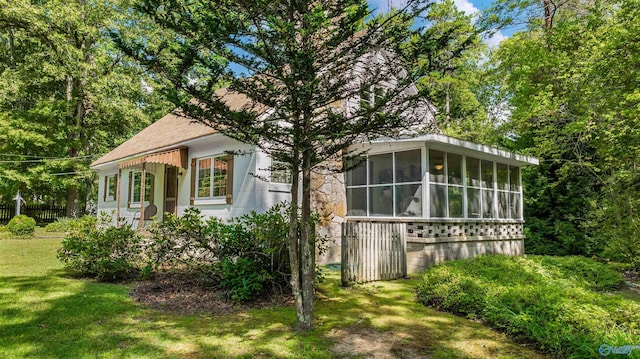 view of property exterior with fence, a yard, a sunroom, and roof with shingles