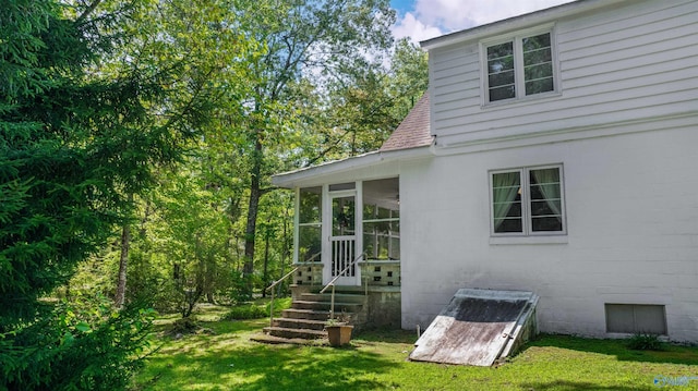 view of side of home featuring a sunroom, a yard, and roof with shingles