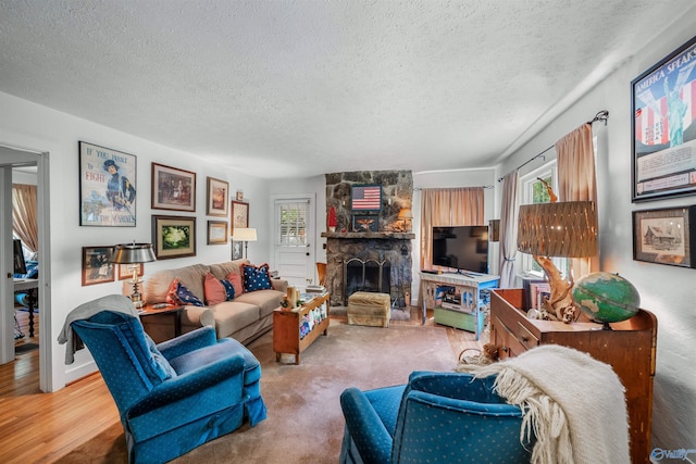 living room with a textured ceiling, wood-type flooring, and a fireplace