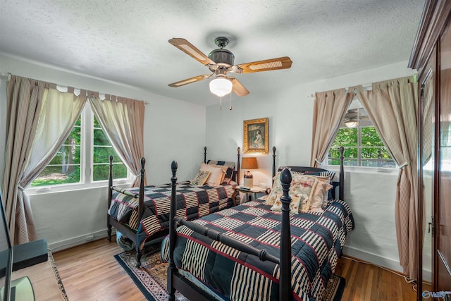 bedroom with baseboards, light wood-type flooring, a ceiling fan, and a textured ceiling