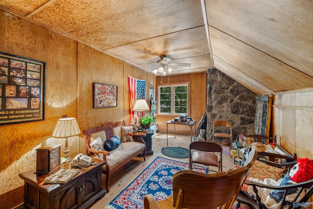 interior space with a fireplace, wood-type flooring, lofted ceiling, ceiling fan, and wooden walls