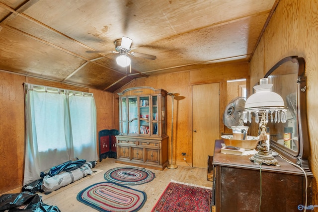 bedroom featuring lofted ceiling, light hardwood / wood-style flooring, and wood walls