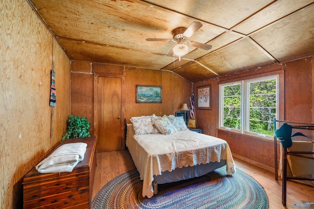 bedroom featuring lofted ceiling, wood finished floors, and wood walls